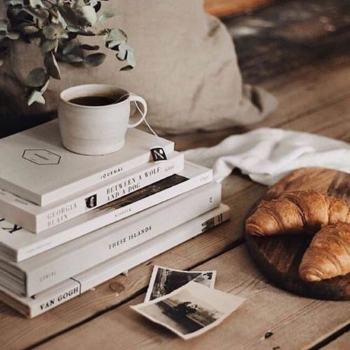 stacked books with coffee and a croissant